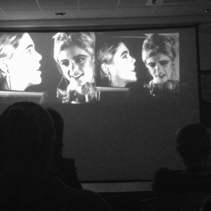 Edie Sedgwick in Andy Warhol's Outer and Inner Space: an audience watches the dual-screen projection of Outer And Inner Space featuring side-by-side images of Edie Sedgwick in front of video monitors with more images of Edie Sedgwick on them.