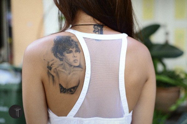 Edie Sedgwick Must Die: photo of a woman's back with an image of Edie Sedgwick tattoo'd on her left shoulder