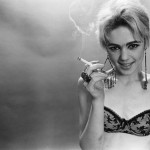 black-and-white photograph of Edie Sedgwick in a black bra and smoking a cigarette