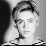 Black and white photo of Edie Sedgwick in a striped top, gazing softly at the camera